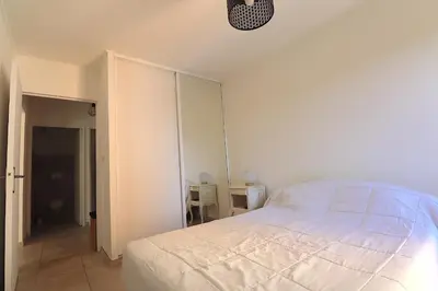 a white bedroom with a bed and a closet at Sublime Appartement avec Parking sur Ajaccio in Ajaccio