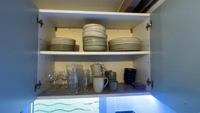 a cupboard with plates and other dishes in it at Chalet climatisé en Haute-Corse 500m plage - camping Marina di Sorbo in Sorbo-Ocagnano