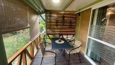 a porch with a table and chairs on a balcony at Chalet climatisé en Haute-Corse 500m plage - camping Marina di Sorbo in Sorbo-Ocagnano