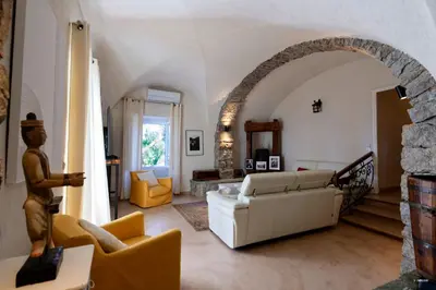 a living room with a white couch and an archway at Maison de maître en pierre de 1831 avec vue sur la mer à Porticcio in Porticcio