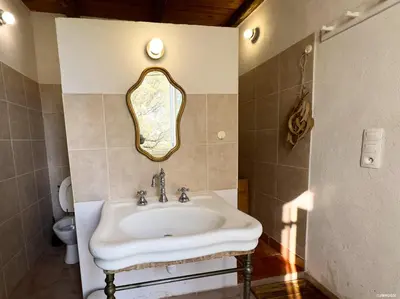 a bathroom with a sink and a mirror on the wall at Maison de maître en pierre de 1831 avec vue sur la mer à Porticcio in Porticcio