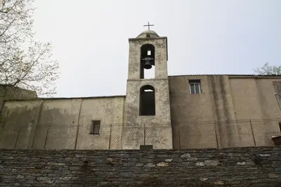 a church with a tower with a cross on top of a wall at Kallista 2 in San-Giuliano