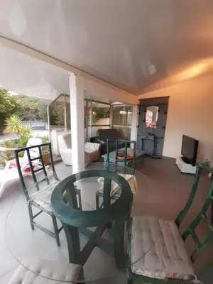 a porch with chairs and a table and a television at Vermentinu T1 bis 50 m plage du Ruppione in Pietrosella