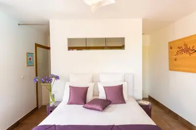 a bedroom with a white bed with purple pillows at Ecrin de Pinarello in Pinarellu