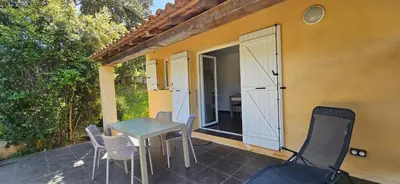 a patio with a table and chairs and a door at T2 Dolce & Vita C3 vue mer et piscine in Propriano