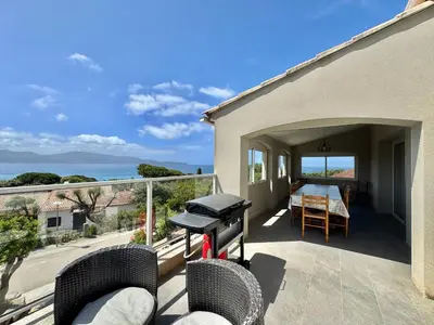 a patio with a grill and chairs on a balcony at Villa le Palmier 10 personnes piscine, vue mer, plage in Olmeto