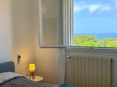 a bedroom with a window with a view of the ocean at Villa le Palmier 10 personnes piscine, vue mer, plage in Olmeto