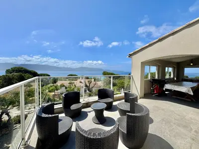 a patio with chairs and a table on a balcony at Villa le Palmier 10 personnes piscine, vue mer, plage in Olmeto