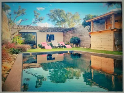 a swimming pool with pink chairs and a house at Villa DOLCE, piscine privée chauffée & jacuzzi privatif, 5mn des plages in Porto-Vecchio