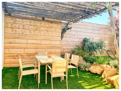 a table and chairs in front of a wooden wall at Villa DOLCE, piscine privée chauffée & jacuzzi privatif, 5mn des plages in Porto-Vecchio