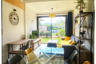 a living room with a table and chairs and a clock at Villa DOLCE, piscine privée chauffée & jacuzzi privatif, 5mn des plages in Porto-Vecchio