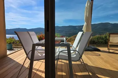 a table and chairs on a deck with an umbrella at Bel Appartement climatisé vue imprenable sur la mer terrasse wifi in Serra-di-Ferro