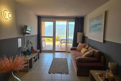 a living room with a couch and a sliding glass door at Bel Appartement climatisé vue imprenable sur la mer terrasse wifi in Serra-di-Ferro