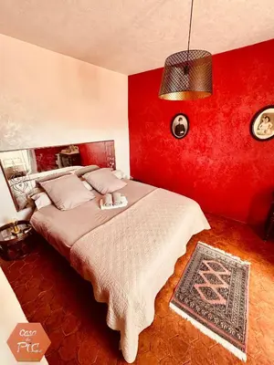 a bedroom with a large bed with a red wall at Casa di Pia, demeure Corse du XIXème in Olmeta-di-Tuda