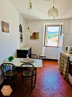 a living room with a table and chairs and a window at Casa di Pia, demeure Corse du XIXème in Olmeta-di-Tuda