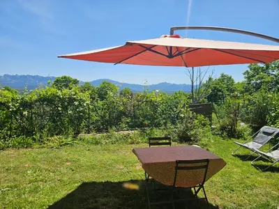 a picnic table with a red umbrella and two chairs at Appartement vue imprenable montagne in Serra-di-Scopamene