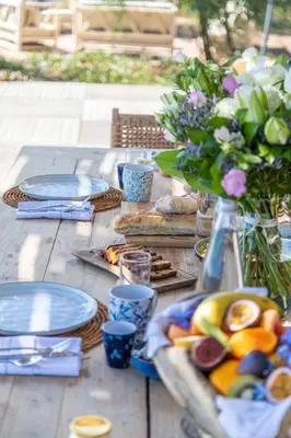 a wooden table with plates of food and flowers at Villa Cala Rossa pieds dans l'eau Porto-Vecchio in Lecci