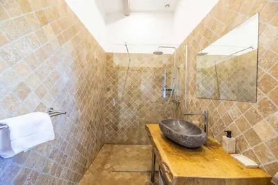 a bathroom with a stone sink on a wooden counter at Villa Cala Rossa pieds dans l'eau Porto-Vecchio in Lecci