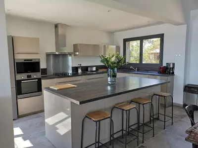 a kitchen with a large island with bar stools at Villa Cala Rossa pieds dans l'eau Porto-Vecchio in Lecci