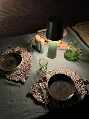 a table with two plates and a lamp on it at Bohemian Villa with Heated Pool near beach in Lecci