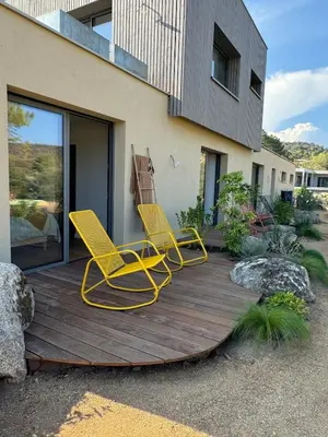 two yellow chairs on a wooden deck in front of a house at Bohemian Villa with Heated Pool near beach in Lecci