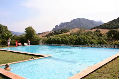 a large swimming pool with mountains in the background at Chambre d'Hôtes Domaine Pero Longo in Sartène