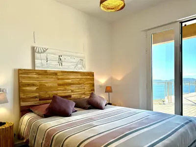 a bedroom with a bed and a view of the beach at Villa Altezza - vue mer 270° in Porto-Vecchio