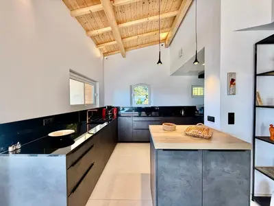 a kitchen with black and white counters and wooden ceilings at Villa Altezza - vue mer 270° in Porto-Vecchio