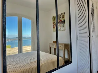 a mirror reflecting a bedroom with a view of the ocean at Villa Altezza - vue mer 270° in Porto-Vecchio