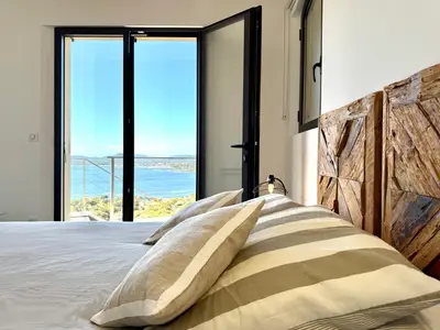a bedroom with a bed with views of the ocean at Villa Altezza - vue mer 270° in Porto-Vecchio