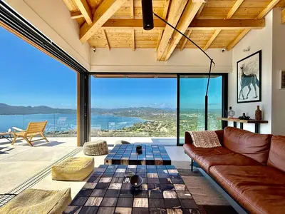 a living room with a couch and a view of the ocean at Villa Altezza - vue mer 270° in Porto-Vecchio