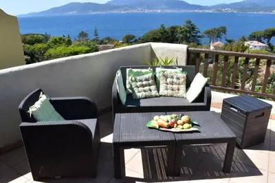 a table and chairs on a balcony with a plate of fruit at Maison familiale vue mer in Grosseto-Prugna