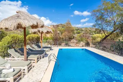 a swimming pool with chairs and umbrellas next to a swimming pool at Villa Rocca Rossa vue exceptionnelle sur la mer in Porto-Vecchio