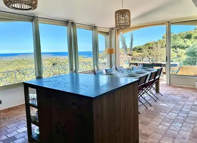 a kitchen with a large island in a room with windows at Villa haut de gamme vue panoramique exceptionnelle in Porto-Vecchio
