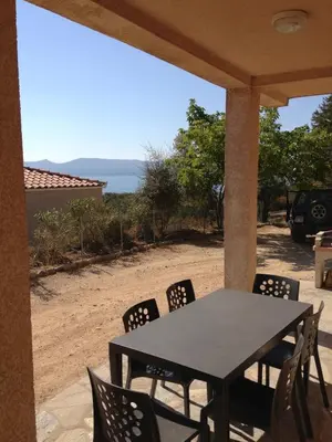 a table and chairs on a porch with a view of the ocean at Casa Soprana in Porto Pollo