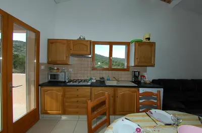 a kitchen with wooden cabinets and a table with a tableablish at Casa Soprana in Porto Pollo