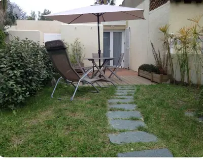 a patio with an umbrella and a table and chair at Studio entre mer et montagne in Taglio-Isolaccio