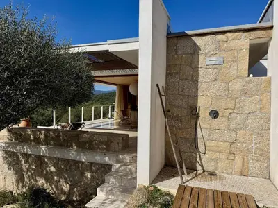 a house with a stone wall and a wooden porch at Villa d'architecte à Abbartello, vue mer et accès plage in Olmeto
