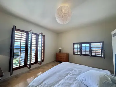 a bedroom with a large white bed and windows at Villa d'architecte à Abbartello, vue mer et accès plage in Olmeto