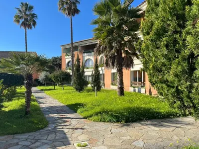 a building with palm trees in front of it at T3 climatisé pour 4 à 6 personnes proche mer en Corse in Linguizzetta