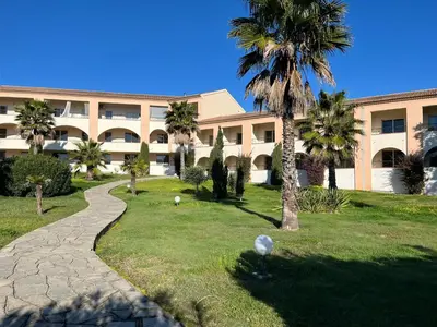 a building with a palm tree and a walkway at T3 climatisé pour 4 à 6 personnes proche mer en Corse in Linguizzetta