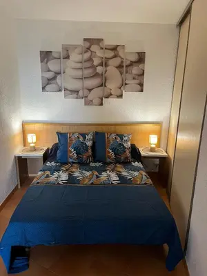 a bedroom with a bed with blue sheets and two lamps at T3 climatisé pour 4 à 6 personnes proche mer en Corse in Linguizzetta