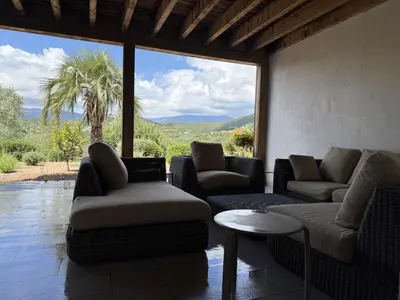 a living room with couches and a large window at kaki in Pinarellu