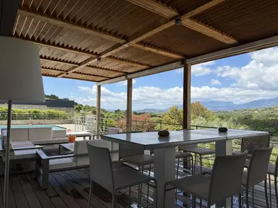 a dining room with a table and chairs on a deck at kaki in Pinarellu