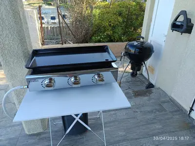 a grill with a table and a bbq smoker at Bord de mer, pieds dans l'eau, vue panoramique in San-Nicolao