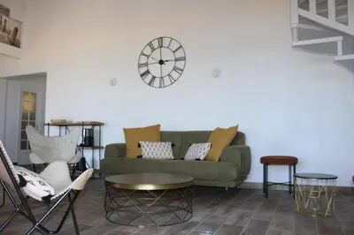 a living room with a green couch and a clock on the wall at Bord de mer, pieds dans l'eau, vue panoramique in San-Nicolao
