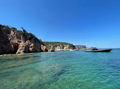 a boat in the water next to a rocky shore at ruscana in Pinarellu