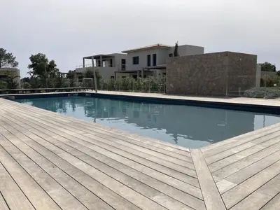 a swimming pool with a wooden deck and a house at tianau in Lecci