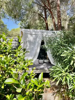 a bed in the middle of some bushes at meli melo in Pinarellu