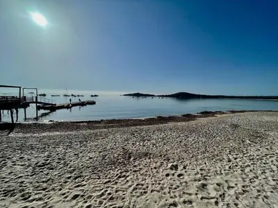 a beach with footprints in the sand and a dock at meli melo in Pinarellu